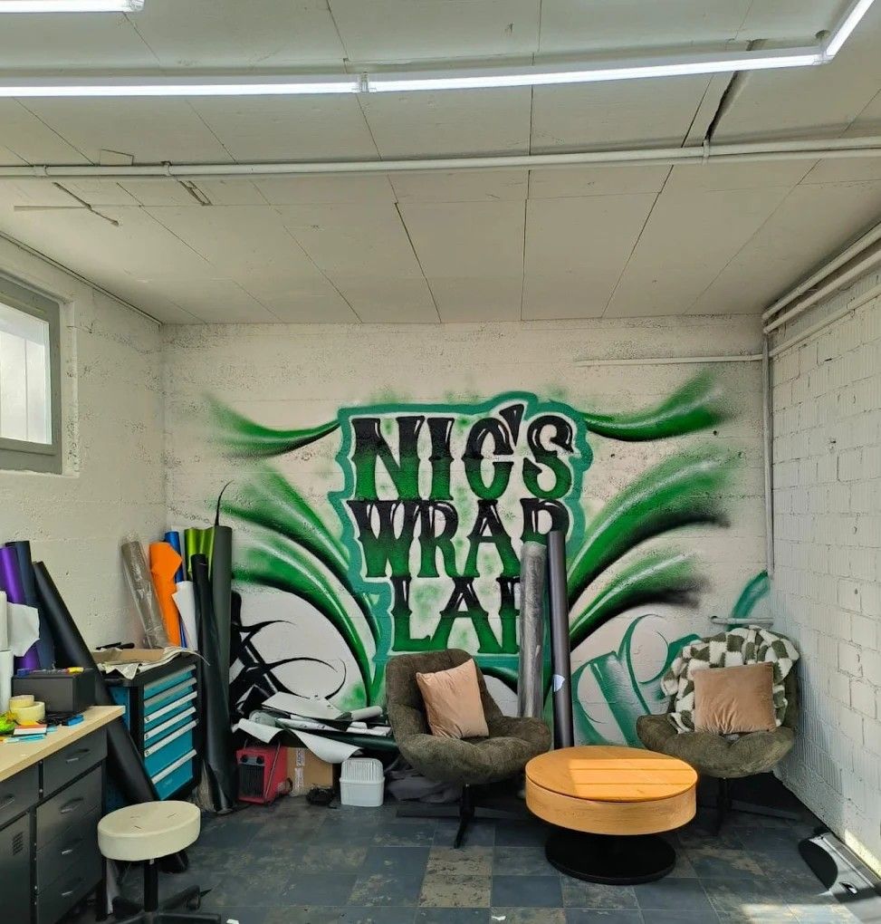 Lounge in der Werkstatt von nic's wrap lab mit grossem Graffiti-Schriftzug an der Wand